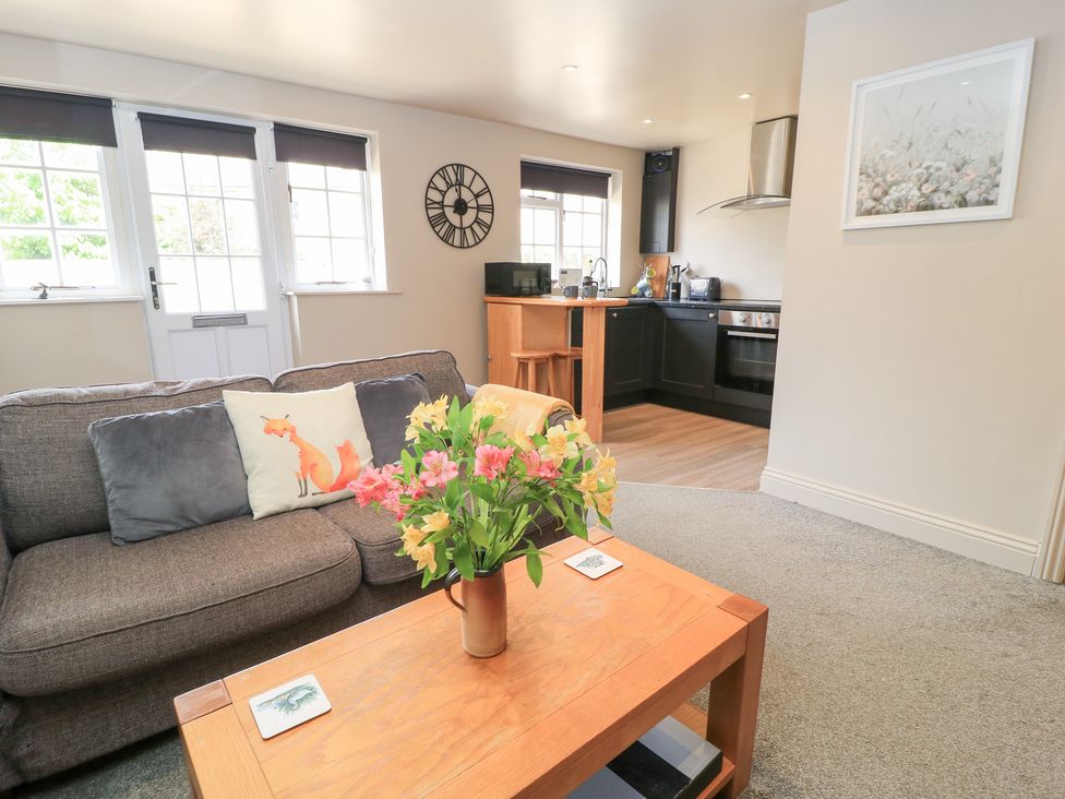 A living room with a sofa and a kitchen area at Well Cottage Nr Malmesbury