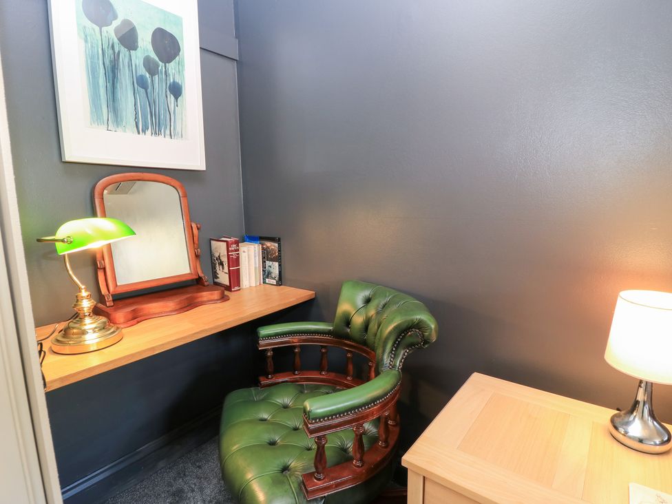 A study with a green chair and a desk at Well Cottage Nr Malmesbury