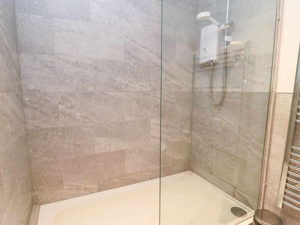 A shower with glass panel and tiles at Well Cottage Nr Malmesbury