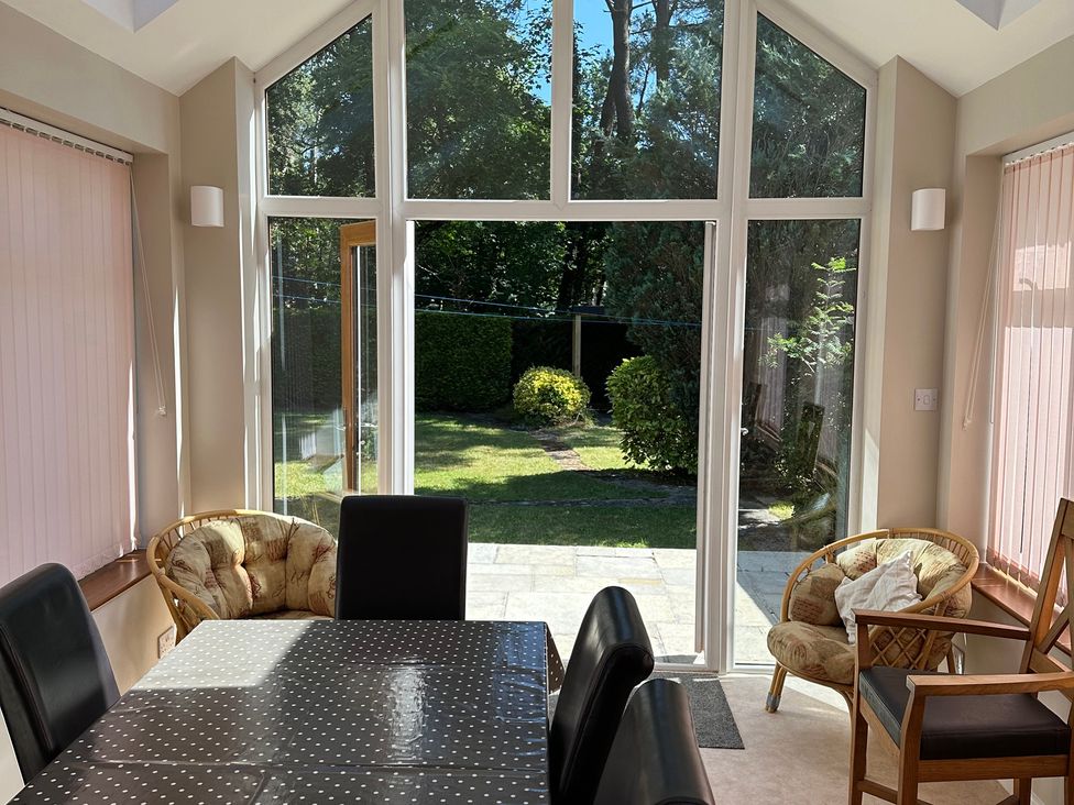 A conservatory with a table and chairs at Pineside in Sandford, Dorset