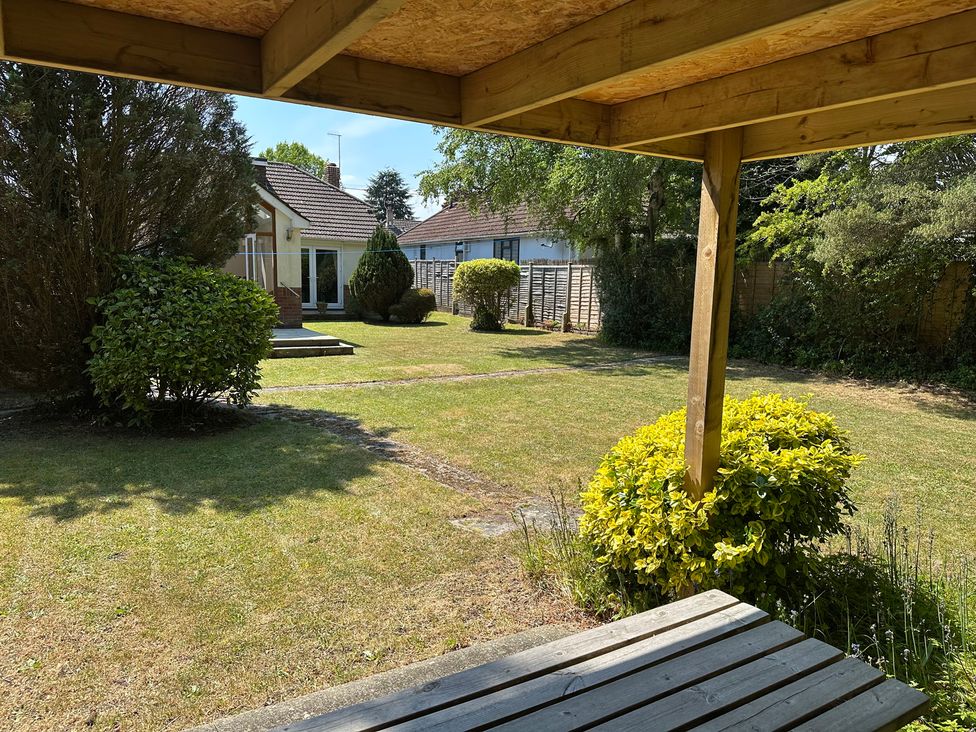 A garden with a house and bushes at Pineside Sandford, Dorset