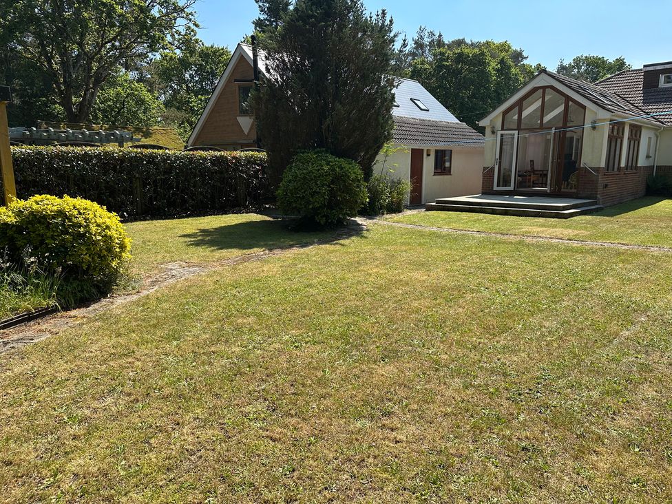 A garden with grass and a house with a patio at Pineside Sandford, Dorset