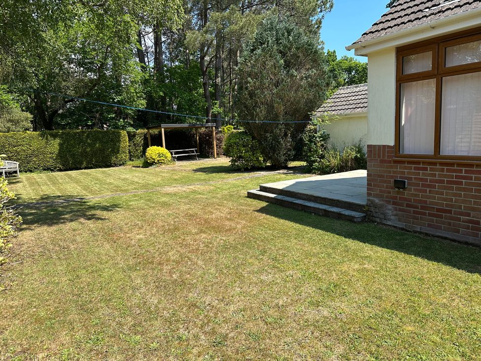 A garden with grass and a seating area at Pineside Sandford, Dorset