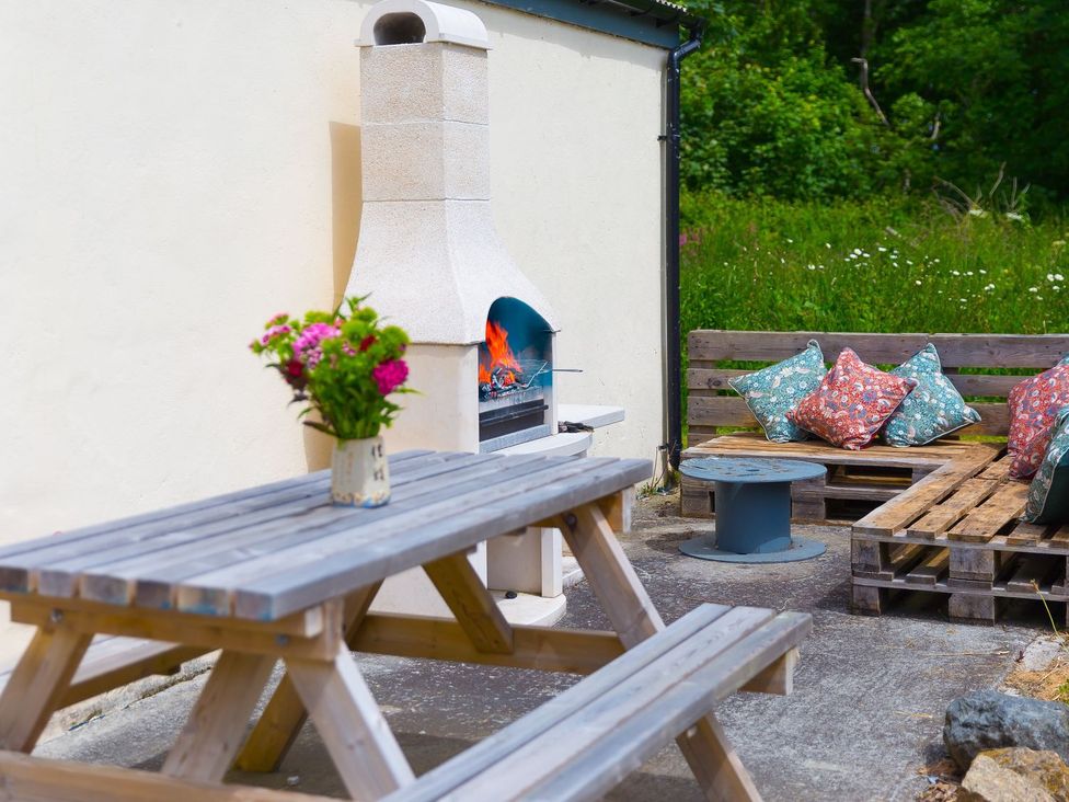 An outdoor seating area with a barbecue grill and picnic table at Carines Barns - Pol, Cubert