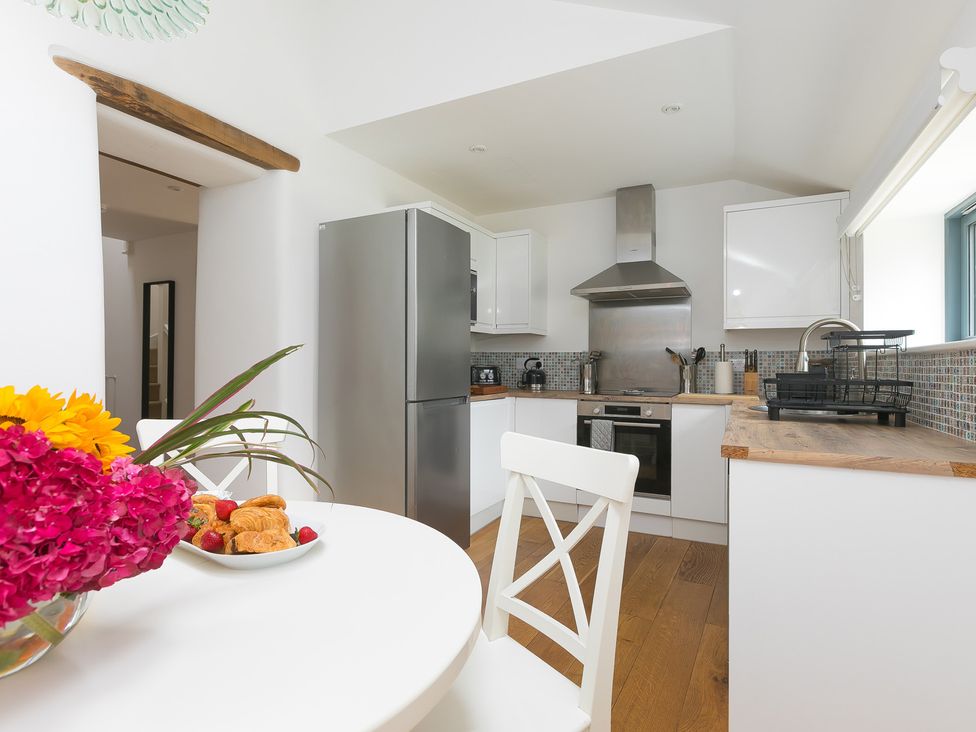 A kitchen with appliances and a dining table at Carines Barns - Pen in Cubert