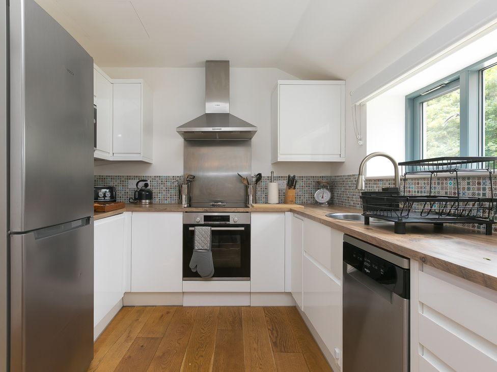A kitchen with modern appliances and wooden countertop at Carines Barns - Pen in Cubert
