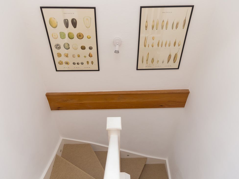 A staircase with posters on the wall at Carines Barns - Pen in Cubert