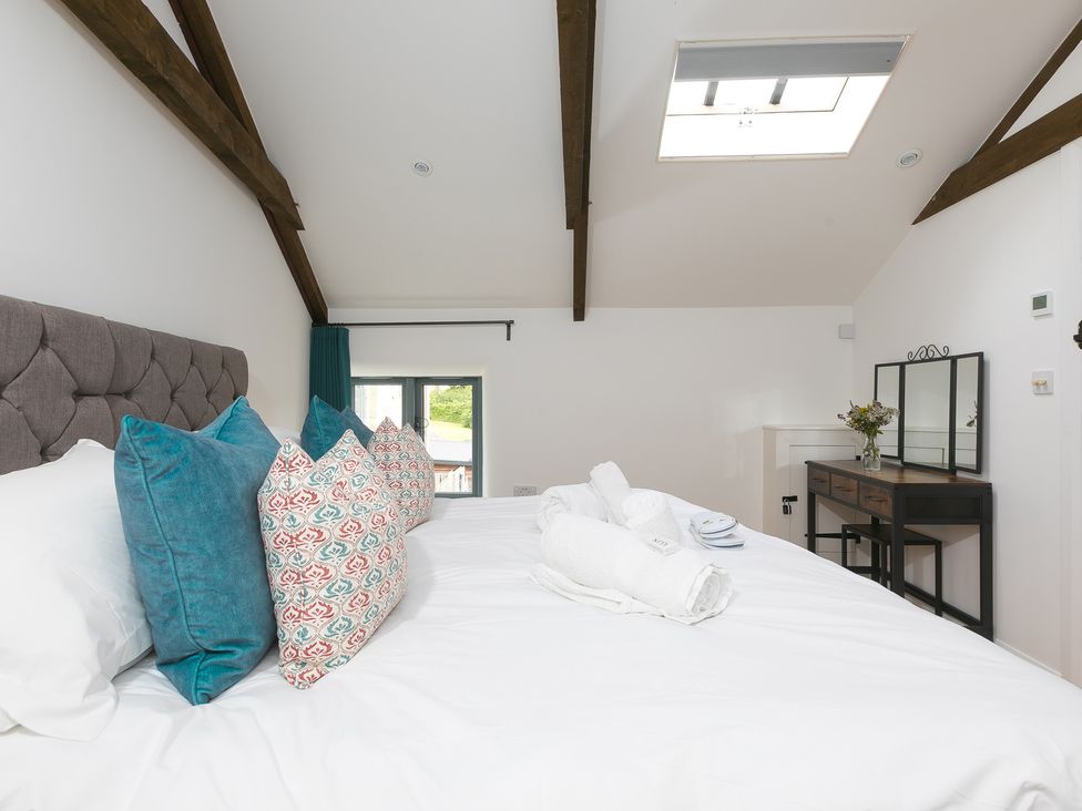 A bedroom with a bed, pillows, and a window at Carines Barns - Pen, Cubert