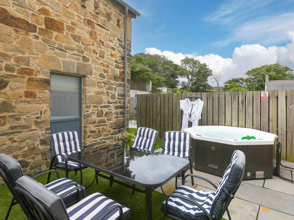 An outdoor seating area with a table and hot tub at Carines Barns - Pen in Cubert