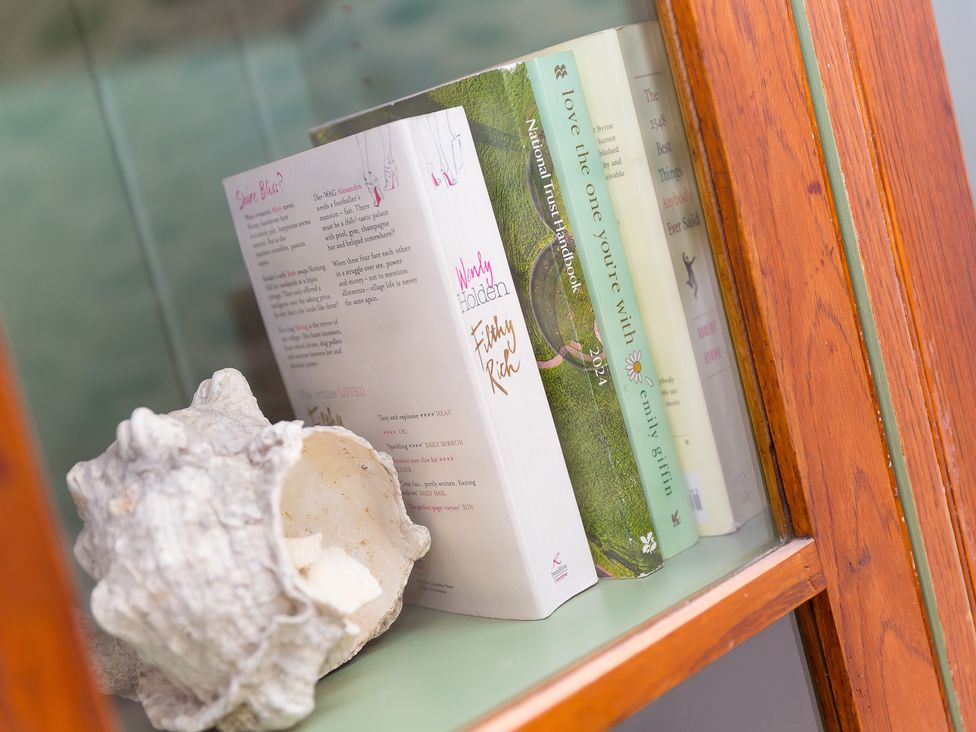A shelf with books and a shell at Carines Barns - Wesley Barn, Cubert