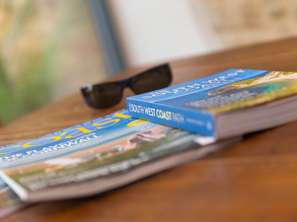 A guidebook and magazines on a wooden table at Carines Barns - Wesley Barn, Cubert