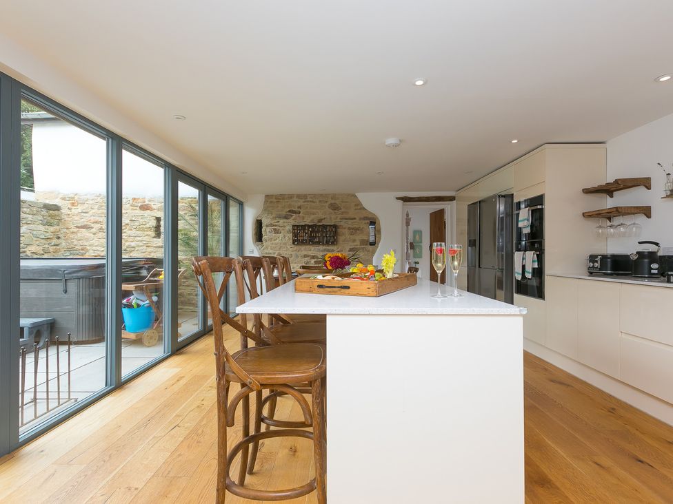 A kitchen with a kitchen island and bar stools at Carines Barns - Wesley Barn in Cubert