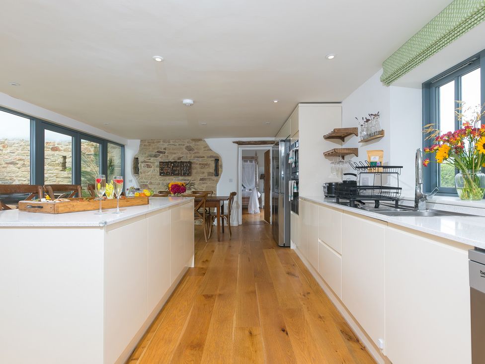 A kitchen with an island and stone wall at Carines Barns - Wesley Barn Cubert