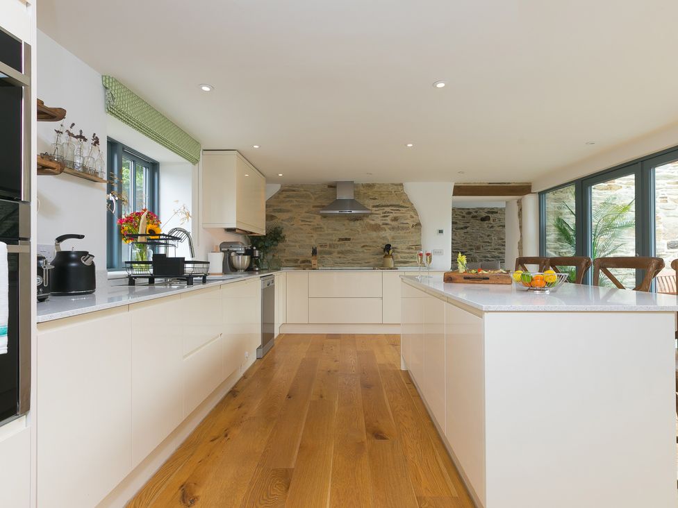 A kitchen with a stone wall and kitchen island at Carines Barns - Wesley Barn, Cubert