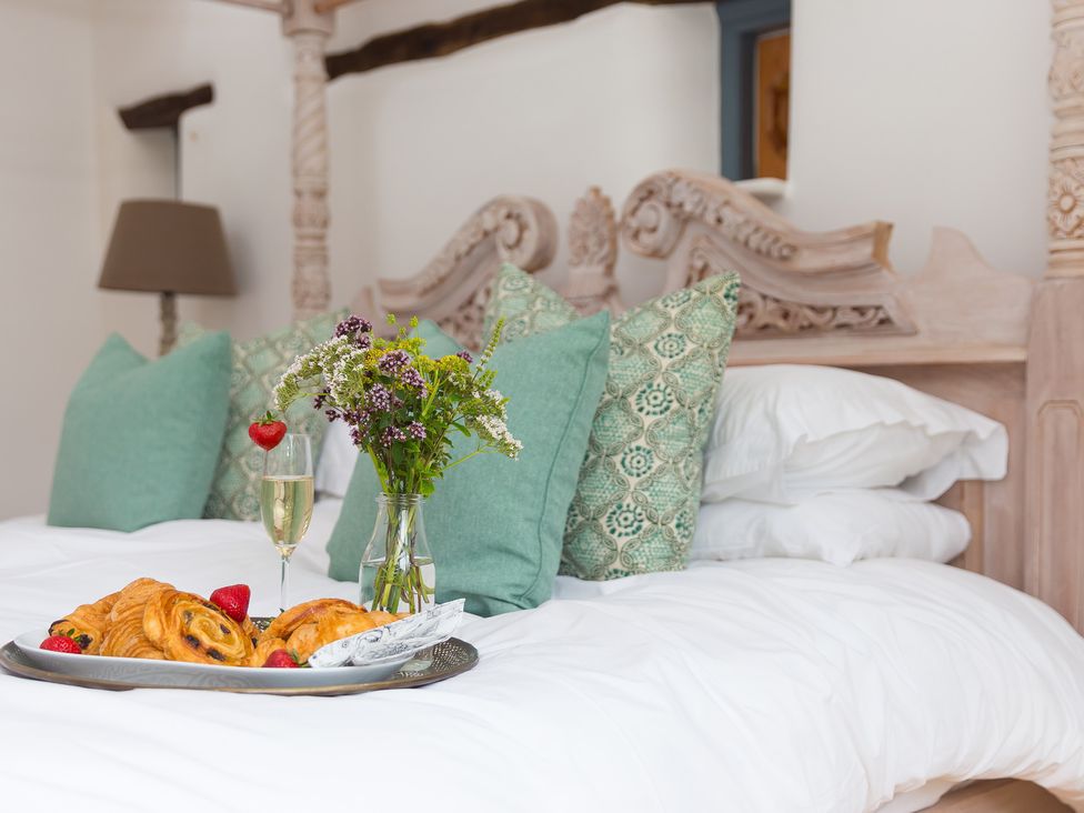 A bedroom with a bed featuring pillows and flowers at Carines Barns - Wesley Barn in Cubert