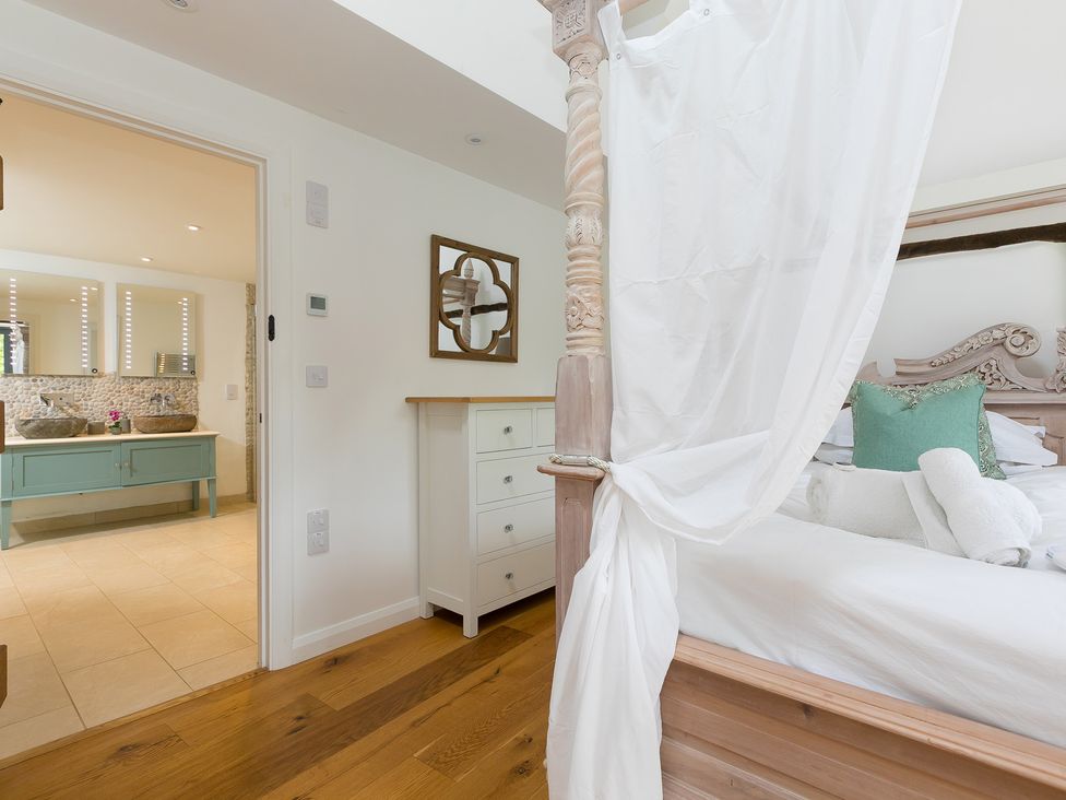 A bedroom with a bed and adjoining bathroom at Carines Barns - Wesley Barn in Cubert