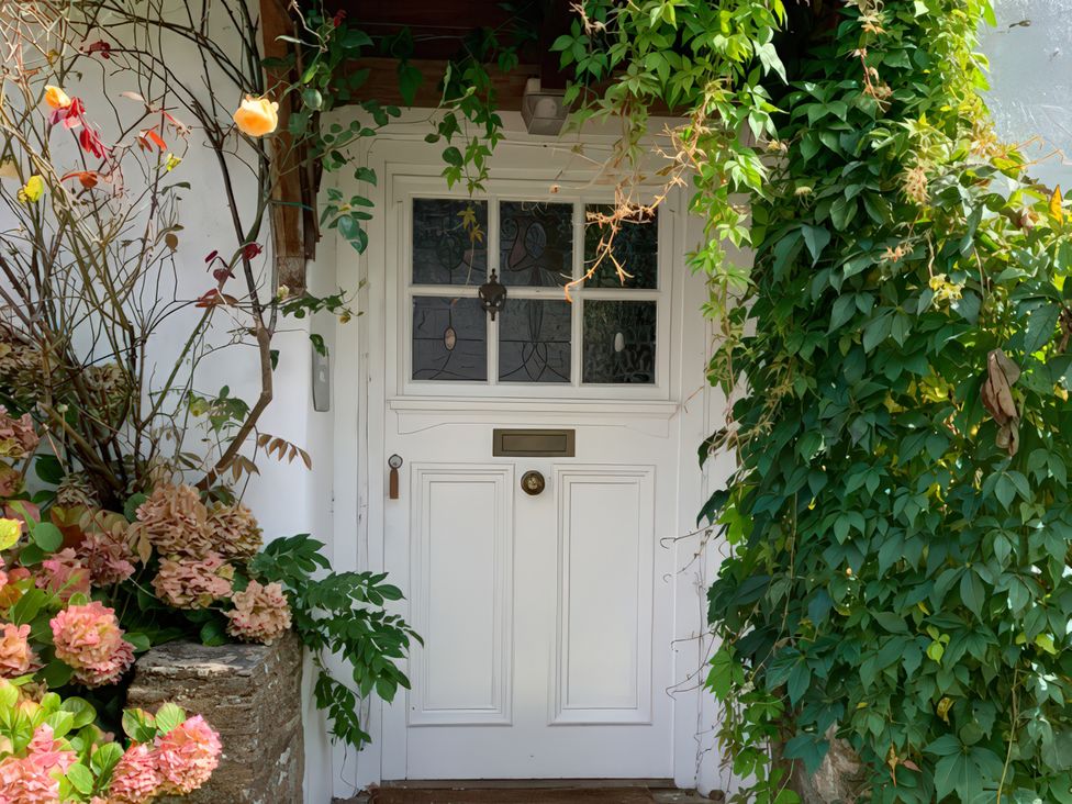 An entrance with a white door and flowering plants at Lower Mill in Dittisham