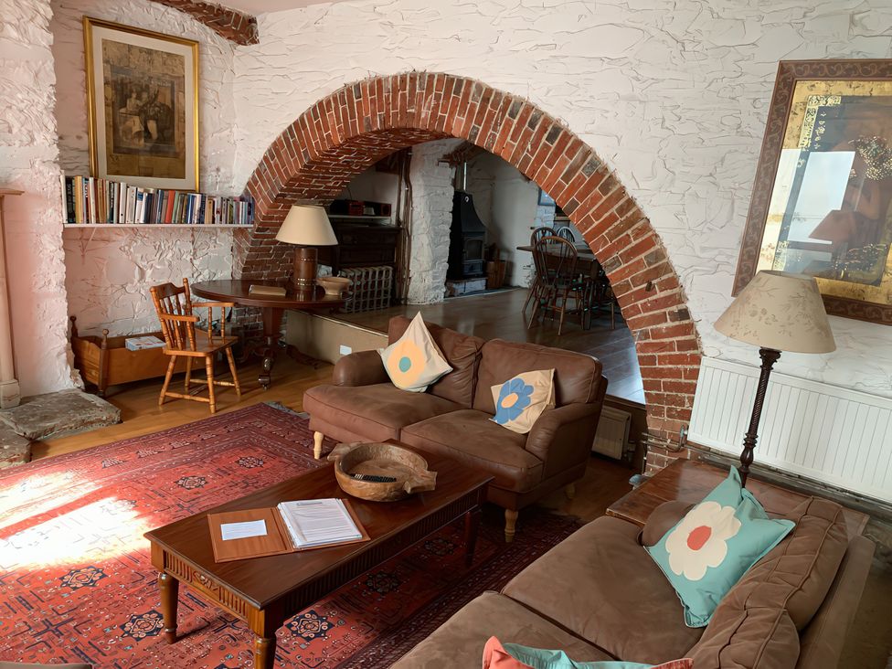 A living room with a sofa, coffee table and bookshelf at Lower Mill in Dittisham