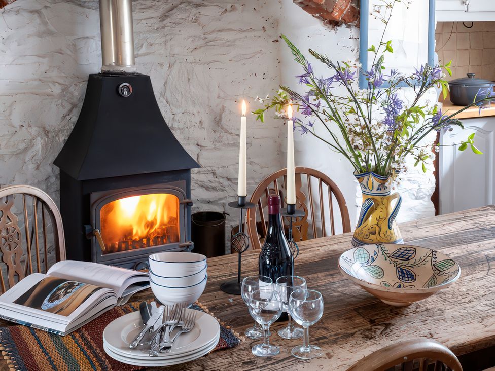 A dining room with a wood stove and a table set for a meal at Lower Mill in Dittisham