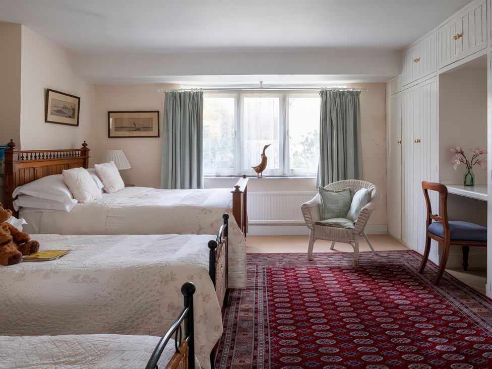 A bedroom with two beds, a chair and a small table at Lower Mill in Dittisham