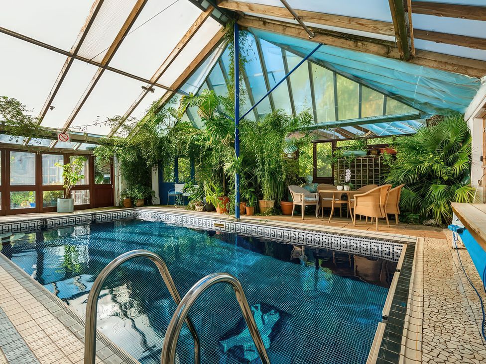 An indoor pool with seating and plants at Lower Mill in Dittisham