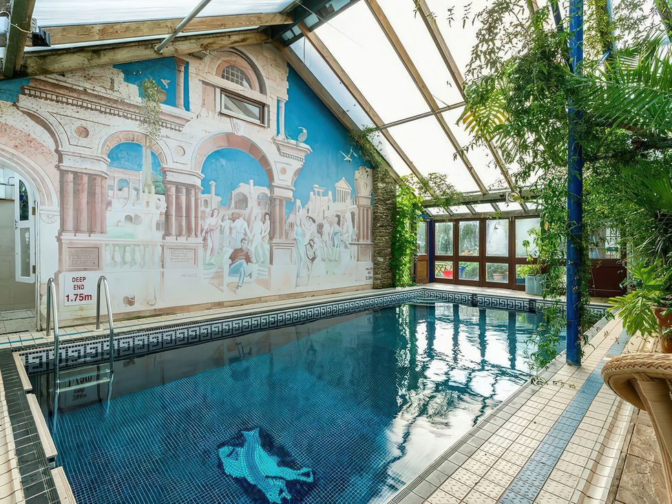 An indoor pool with a mural and plants at Lower Mill in Dittisham