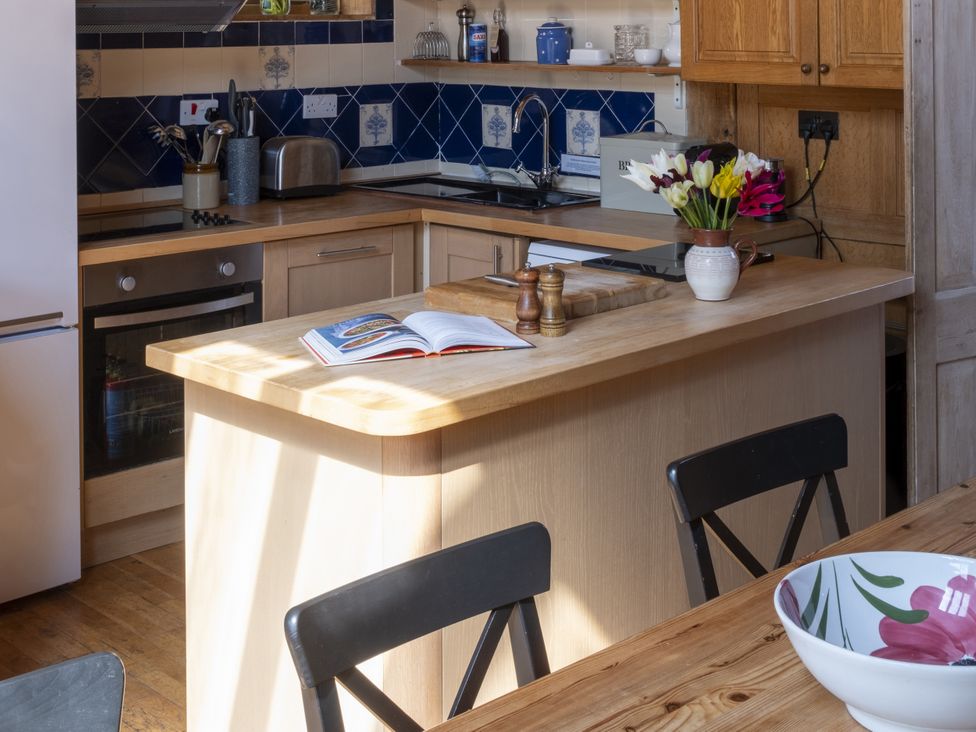 A kitchen with an island, utensils, and a dining table at The Barn in Dittisham