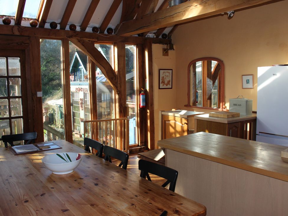 A kitchen with a table and chairs and a refrigerator at The Barn in Dittisham