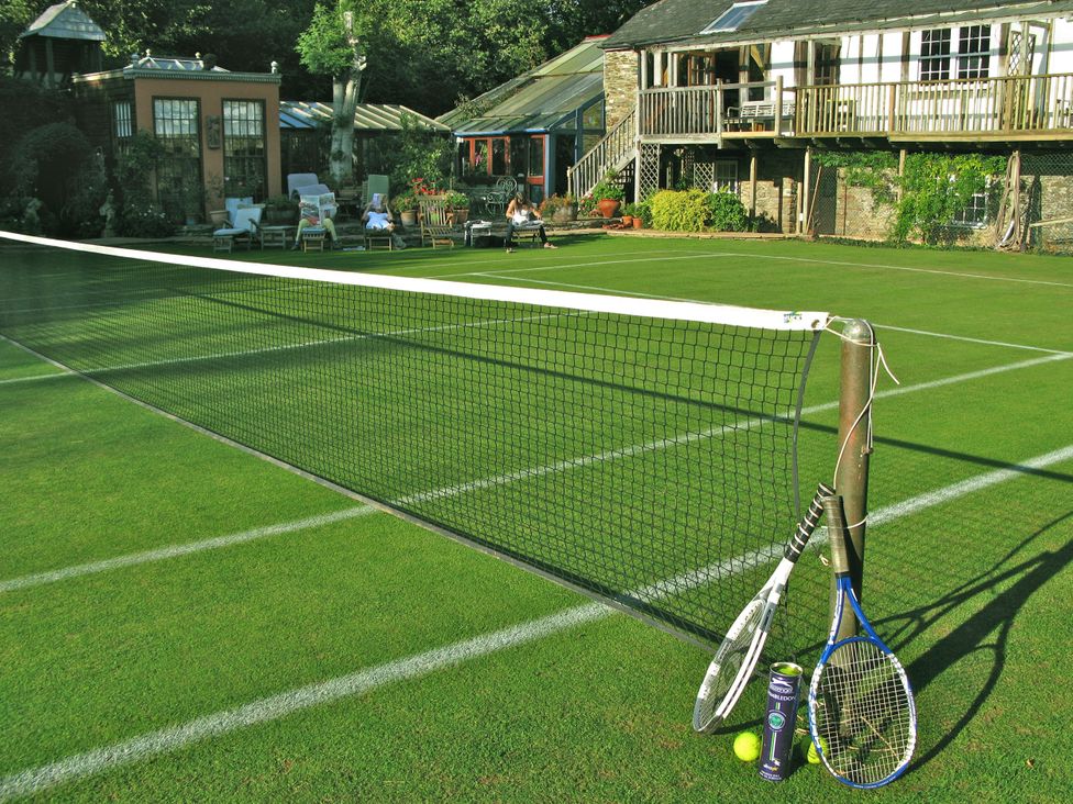 A tennis court with a net and rackets at The Barn in Dittisham