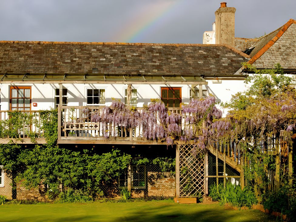 A building with a balcony and wisteria at Wisteria Suite in Dittisham