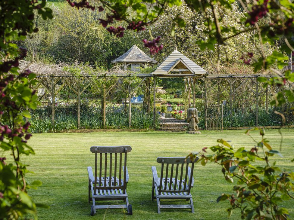 A garden with chairs and a pergola at Wisteria Suite Dittisham