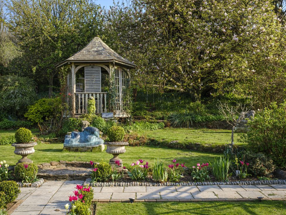 A garden with a gazebo and flower beds at Wisteria Suite Dittisham