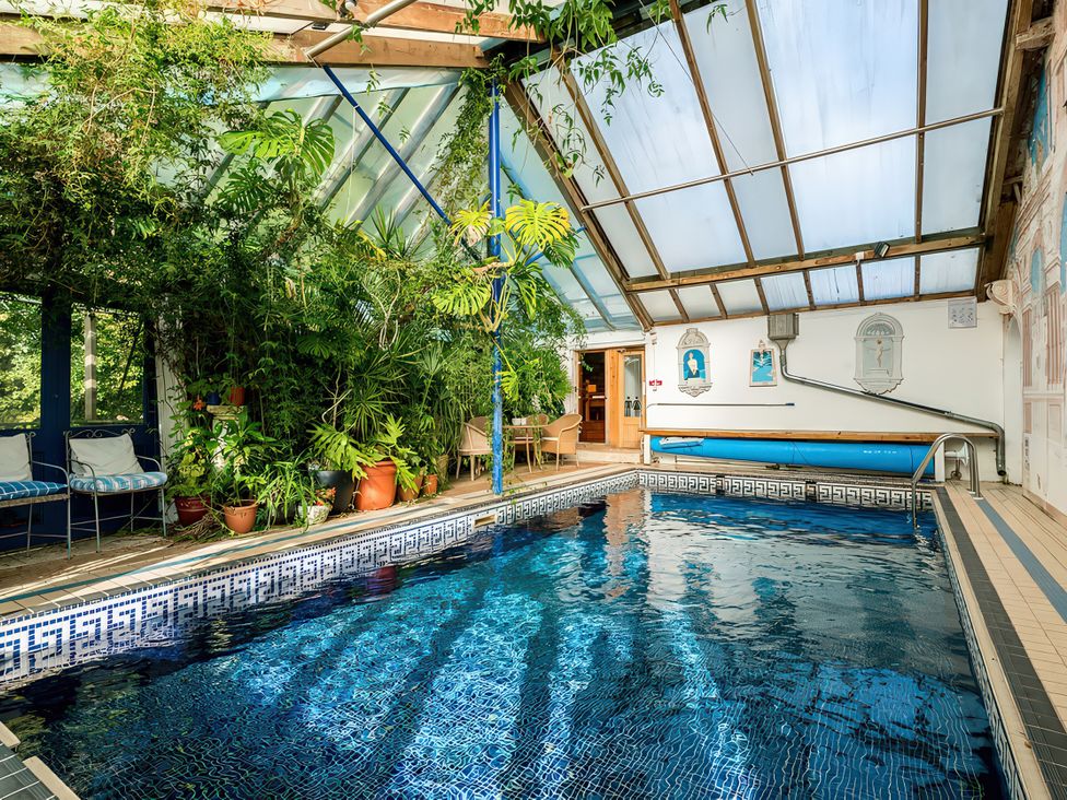 An indoor pool surrounded by plants and seating at Barberry Brook in Dittisham
