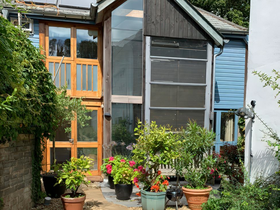 A garden with potted plants and a house at Barberry Brook in Dittisham