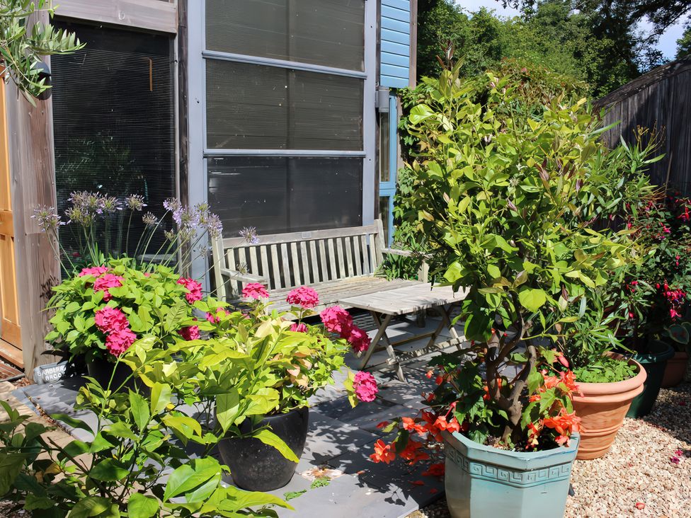An outdoor area with a bench and various flower pots at Barberry Brook in Dittisham