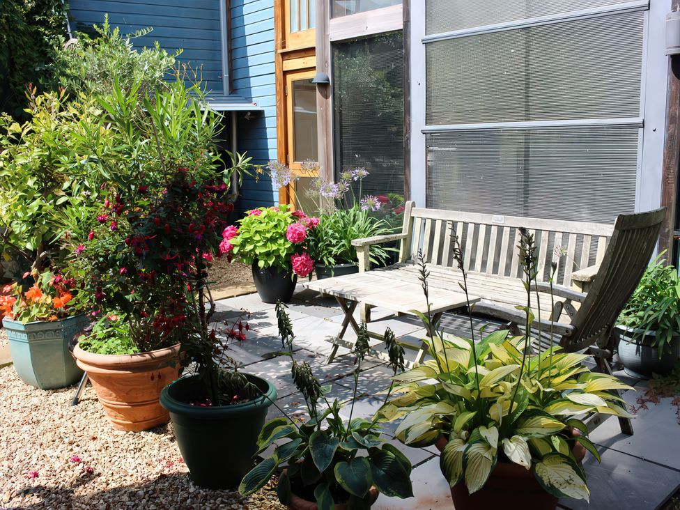 A garden with potted plants and a wooden bench at Barberry Brook in Dittisham