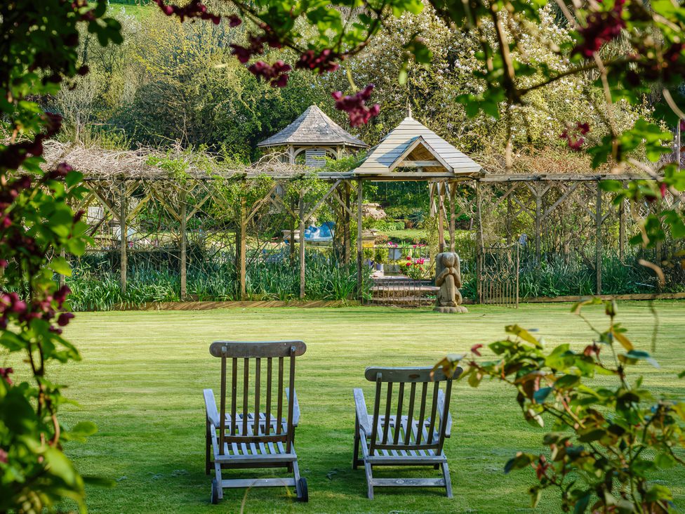 A garden with chairs and a pergola at Barberry Brook in Dittisham