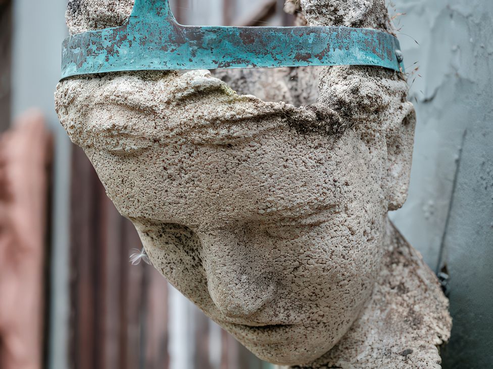 A sculpture of a head with a metal band at Barberry Brook in Dittisham