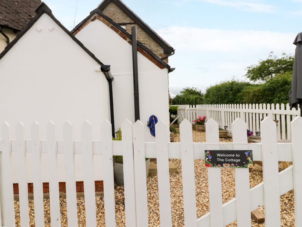 An outdoor area with a white fence and a sign at The Cottage in Ettington