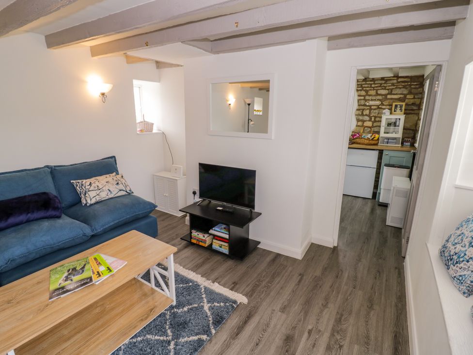 A living room with a sofa, coffee table, and television at The Cottage in Ettington