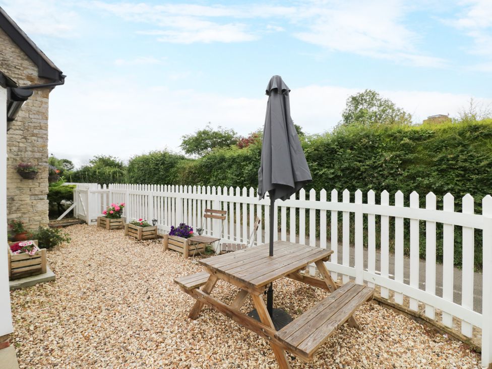 A garden with a wooden table and umbrella at The Cottage in Ettington