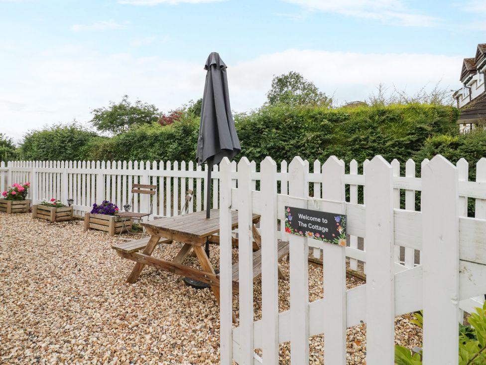 A garden with a table and umbrella at The Cottage in Ettington