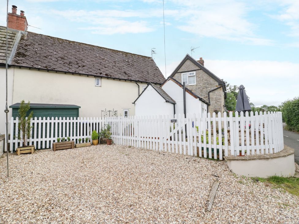 An outdoor area with a house and white picket fence at The Cottage in Ettington