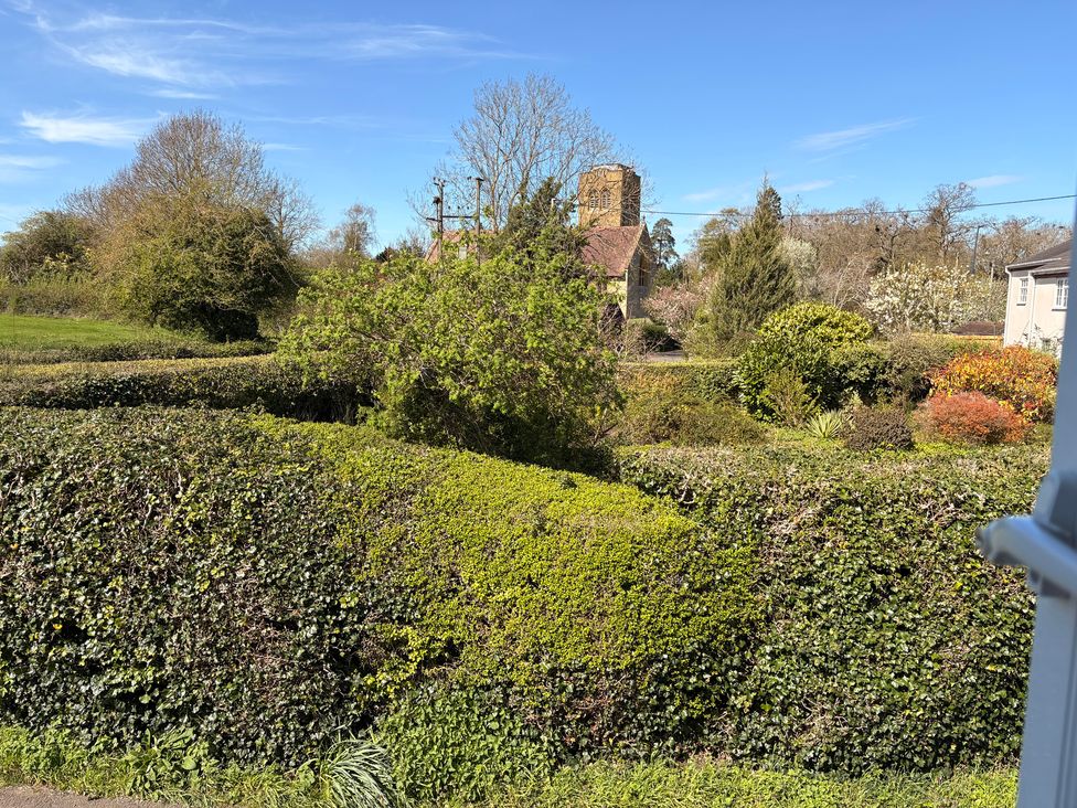 A view of hedges and trees near a building at The Cottage in Ettington