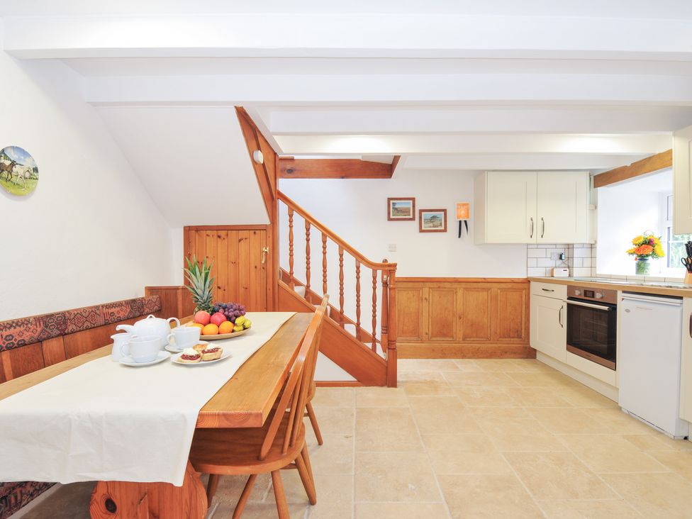 A kitchen with a dining area and staircase at Henwood Barn Henwood near Upton Cross