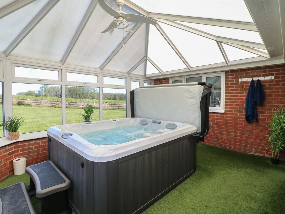 A conservatory with a hot tub and plants at Tixall Manor Farm in Tixall near Great Haywood