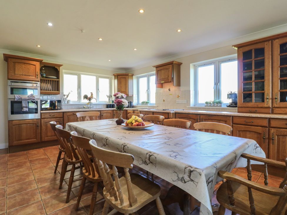 A kitchen with a dining table and wooden chairs at Tixall Manor Farm in Tixall near Great Haywood