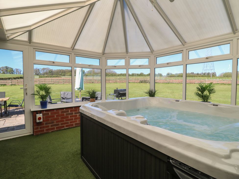 A conservatory with a hot tub and patio furniture at Tixall Manor Farm Tixall near Great Haywood