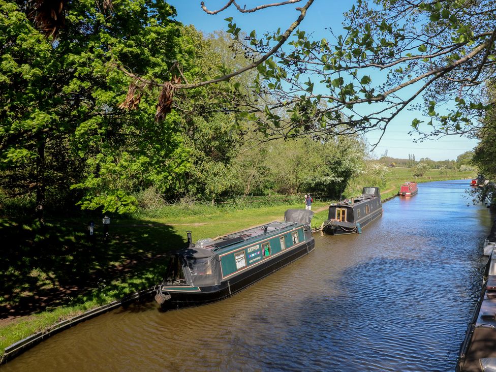 Narrowboats on a canal with trees and a pathway at Tixall Manor Farm Tixall near Great Haywood