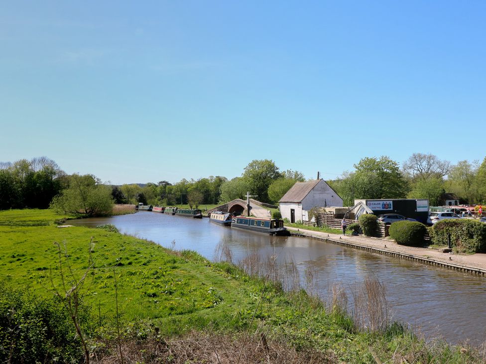 A canal with narrowboats and a footbridge at Tixall Manor Farm in Tixall near Great Haywood